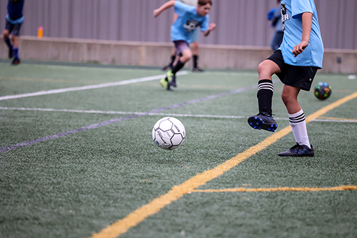 Photo of young people kicking a soccer ball